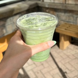 a person holding an iced matcha