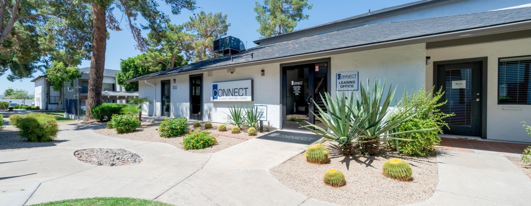 a building with a sign and plants in front of it